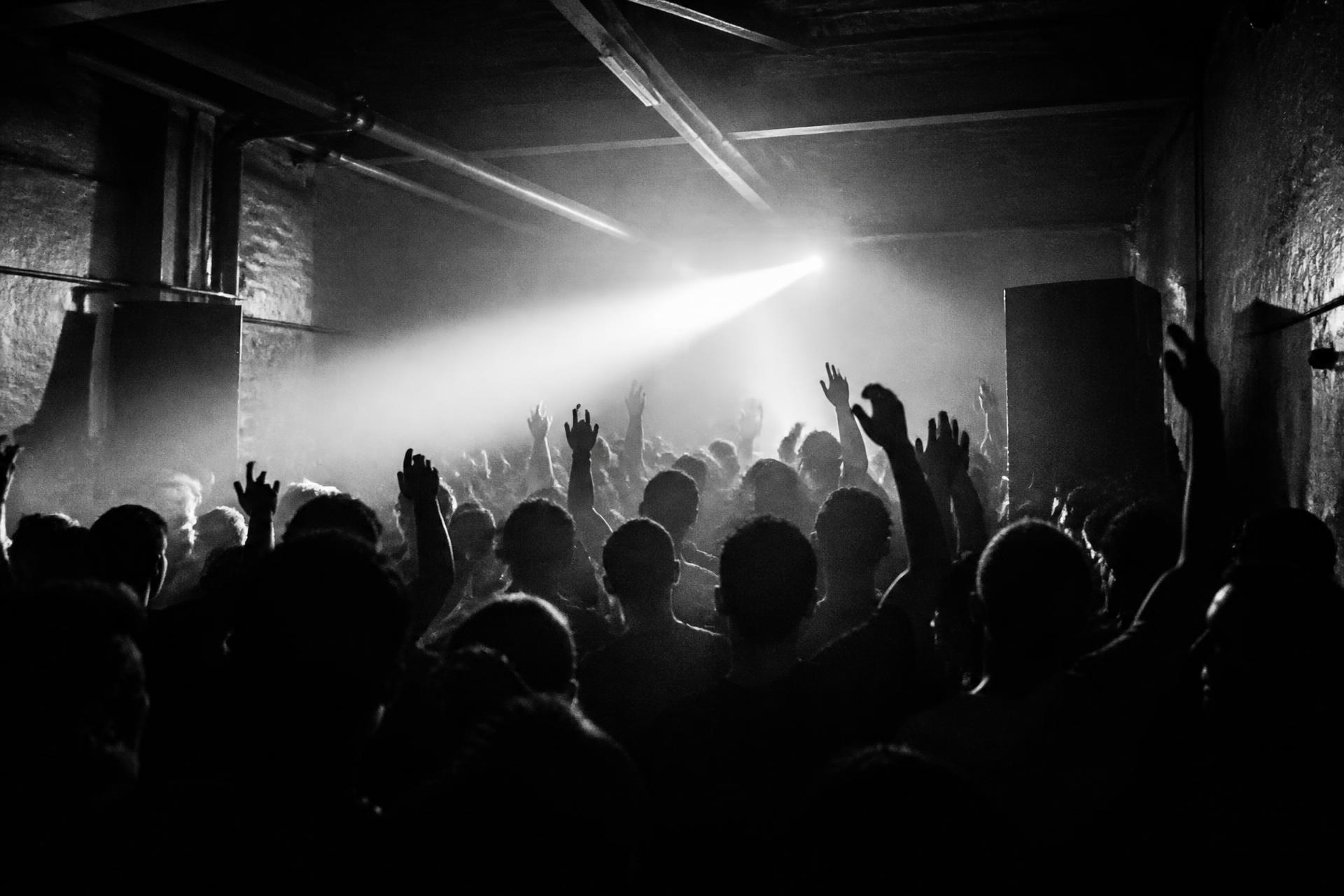Packed underground warehouse crowd cut by a single strobe beam